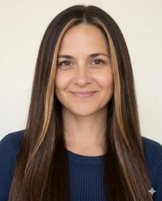 Create a realistic portrait using the uploaded photo, keeping the face and features exactly the same. Change only the hair to long, straight hair in a dark brown shade with two lighter blonde money-piece highlights framing the front of the face. The person faces forward with a relaxed, natural expression. Use eye-level framing with soft daylight and a clean background. Keep skin tone and facial features identical and the result fully photorealistic. Use aspect ratio 4:5.