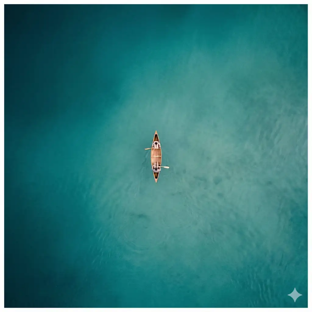 Create a top-down aerial minimalist photograph of a small canoe floating in the center of an expansive body of water. The water fills nearly the entire frame, transitioning subtly from deep teal to lighter turquoise tones, with soft ripples and gentle texture visible beneath the surface. The vast negative space emphasizes calm, isolation, and scale. At the exact center of the composition, a narrow canoe is seen from directly above. Two people sit inside the boat, aligned lengthwise, holding paddles that rest lightly against the water. Their presence feels quiet and still, almost suspended in time. Use aspect ratio 1:1.