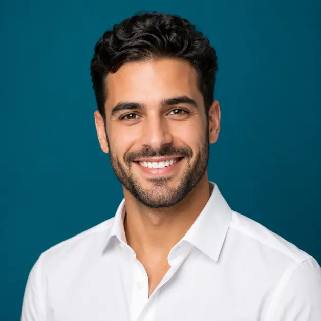 Create a vibrant professional headshot of a person against a solid deep teal background. They are wearing a crisp white shirt with a relaxed collar, standing with confident posture and a friendly smile. Their expression is bright and approachable, looking directly into the camera. The camera is at eye level with a head-and-shoulders crop. Even studio lighting with a clean finish. The mood is energetic, modern, and confident. Use aspect ratio 1:1.