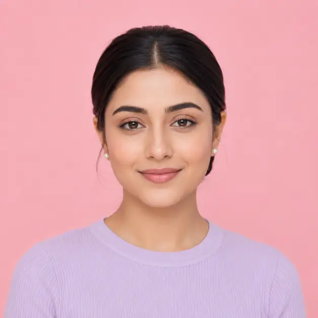 Create a minimal portrait of a woman in her 20s, framed from the shoulders up. She faces the camera with a serene, closed-lip smile, posture upright and relaxed. She wears a pale lavender ribbed top with tiny pearl earrings, hair in a sleek center-parted low bun with soft natural makeup. Shoot at eye level with a shallow depth of field. Lighting is soft, even, and shadowless, like a bright overcast day in a studio. The background is a smooth pastel pink studio backdrop with no texture. The style is clean, minimal, and contemporary with gentle color harmony. Use aspect ratio 1:1.